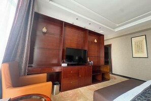 Une chambre d’hôtel équipée d’une télévision, d’un meuble de rangement en bois, d’un canapé et d’un lit.