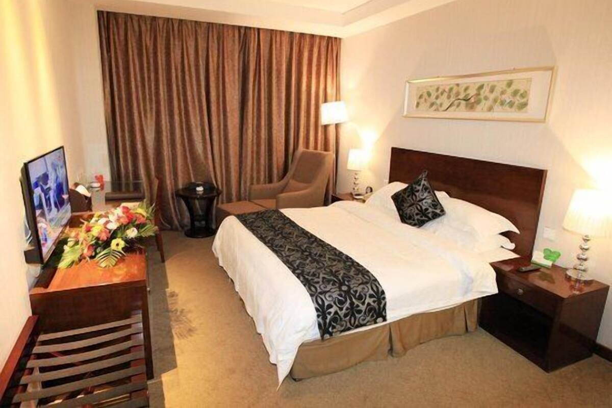 Une chambre d’hôtel avec un lit, une chaise, un bureau, une lampe et un tableau au mur.