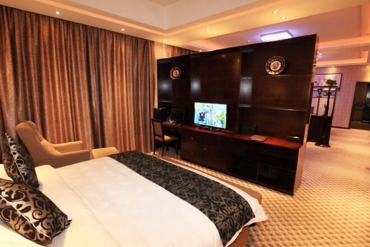 Une chambre d’hôtel avec un lit, une télévision, un bureau et une chaise.
