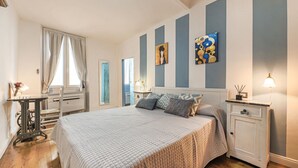 A bedroom with a bed, bedside tables, a desk, and a window with curtains. - Apartments Florence - Blue Serendipity (Firenze)