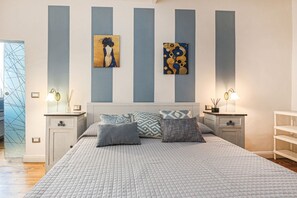 Quarto com uma cama grande, duas mesas de cabeceira, uma cabeceira e uma obra de arte na parede.