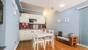 A compact kitchen with white cabinets, a dining table, and a sofa. - Apartments Florence - Blue Serendipity (Firenze)