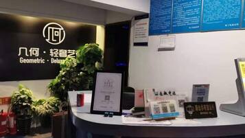 A reception desk with a logo, a framed certificate, informational cards, and a QR code.