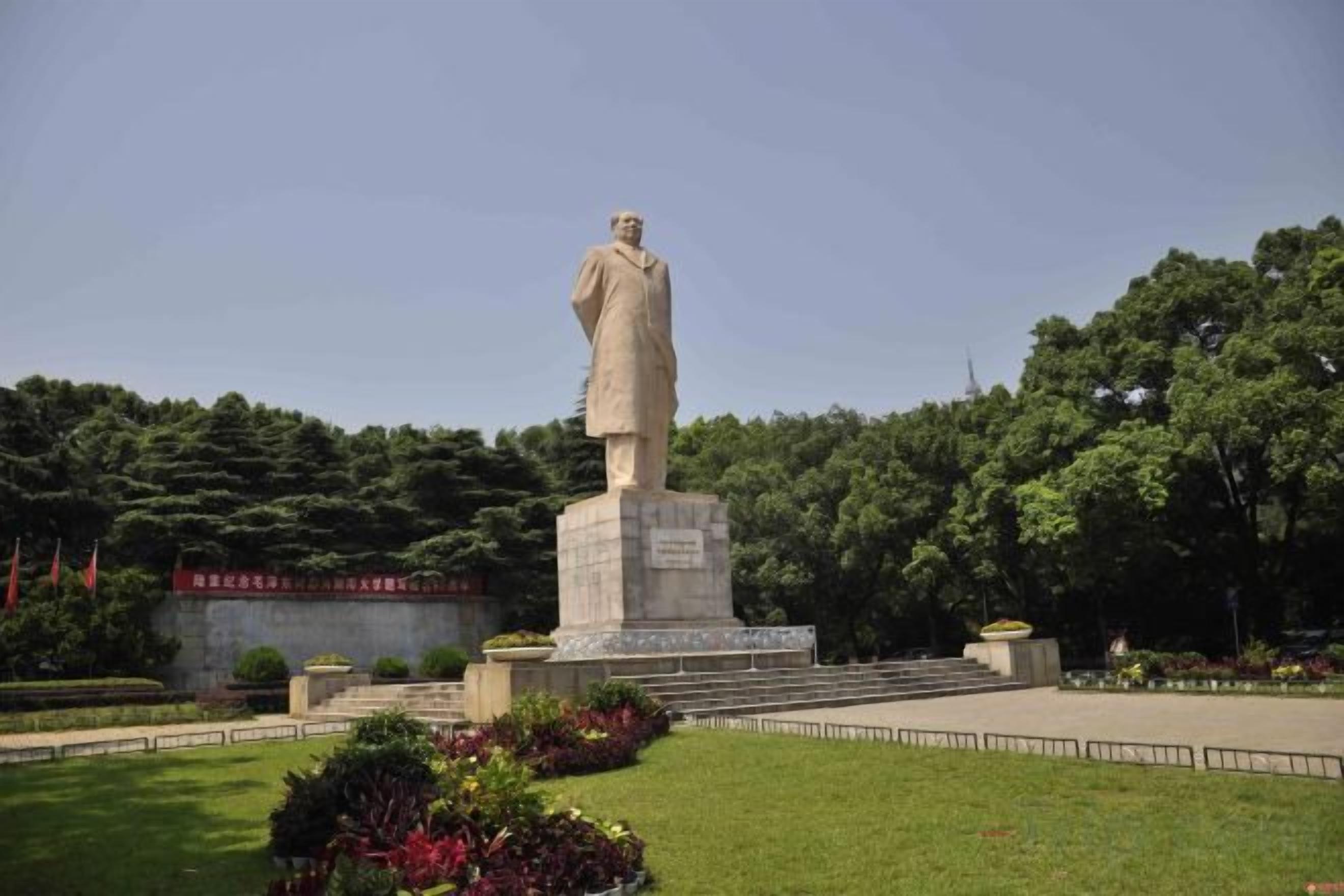 A statue in a park with steps leading up to it, surrounded by greenery.