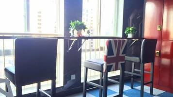 A room with a window, a table, and chairs. There are potted plants on the windowsill.