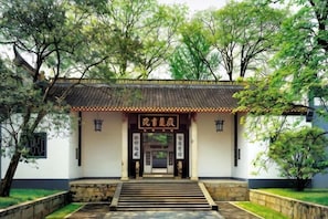 A traditional building with a tiled roof, a stone staircase leading to the entrance, and a signboard with Chinese characters. - Jihe Light Luxury Art Hotel（Wuyi Square Station） (Changsha)