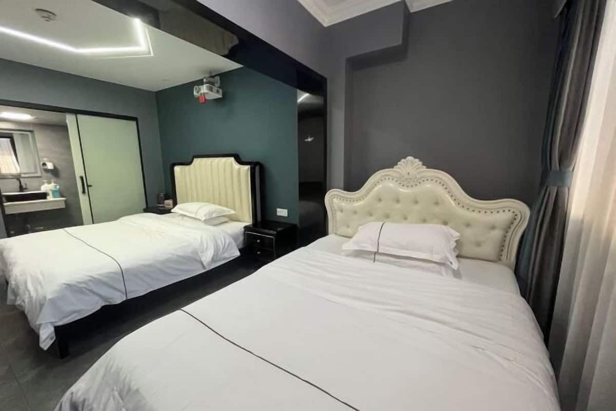 A hotel room with two beds, a mirror, a nightstand, and a wardrobe.