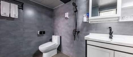 Uma casa de banho moderna com sanita, chuveiro e lavatório.