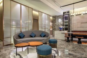 Un hall d’entrée moderne avec un canapé, deux tables rondes et un banc.