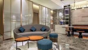 A modern lobby with a sofa, two round tables, and a bar area. - Orange Hotel (Shanghai Hongqiao Railway Station Qixin Road) (Shanghai)