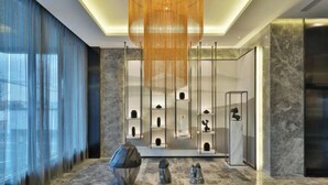 A modern lobby with a marble floor, a large hanging light fixture, and a display of sculptures. - Orange Hotel (Shanghai Hongqiao Railway Station Qixin Road) (Shanghai)