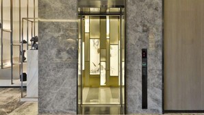 An elevator with a glass panel, marble walls, and a control panel. - Orange Hotel (Shanghai Hongqiao Railway Station Qixin Road) (Shanghai)