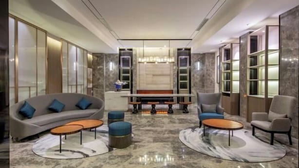 A modern lobby with a sofa, chairs, a bench, and a chandelier. - Orange Hotel (Shanghai Hongqiao Railway Station Qixin Road) (Shanghai)