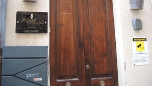Puerta doble de madera con una placa en la parte superior, un buzón y dos macetas a cada lado.