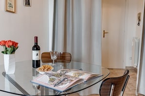 A glass table with a wine bottle, a bowl of pasta, and an open magazine. - Balcone sul Verde - Sweet Dreams in Florence (Firenze)