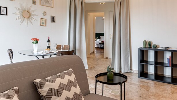 A living room with a sofa, a small table with a vase, and a black console table with decorative items. - Balcone sul Verde - Sweet Dreams in Florence (Firenze)