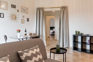 A living room with a sofa, a small table with a vase, and a black console table with decorative items. - Balcone sul Verde - Sweet Dreams in Florence (Firenze)