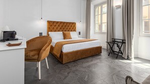 A hotel room with a bed, a desk, a chair, and a small table.