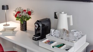 Hotelkamer met koffiezetapparaat, vaas met bloemen, dienblad met kopjes en een afstandsbediening.