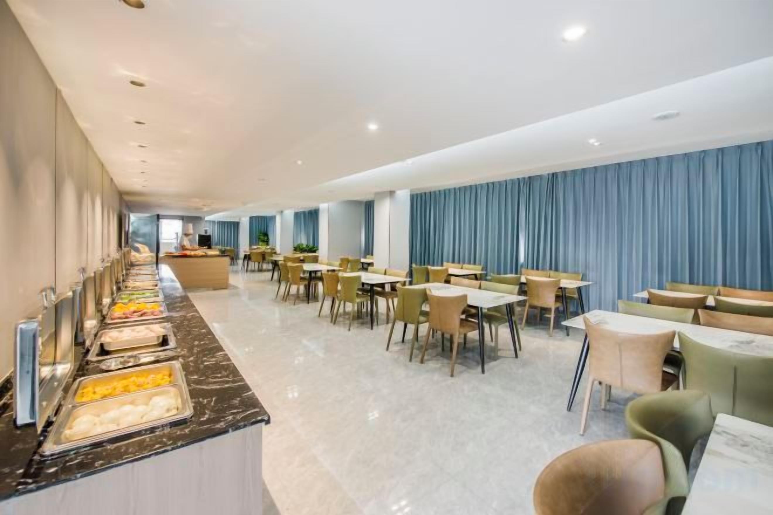 Un comedor de hotel con servicio de buffet, arreglos de mesas y vistas al salón.