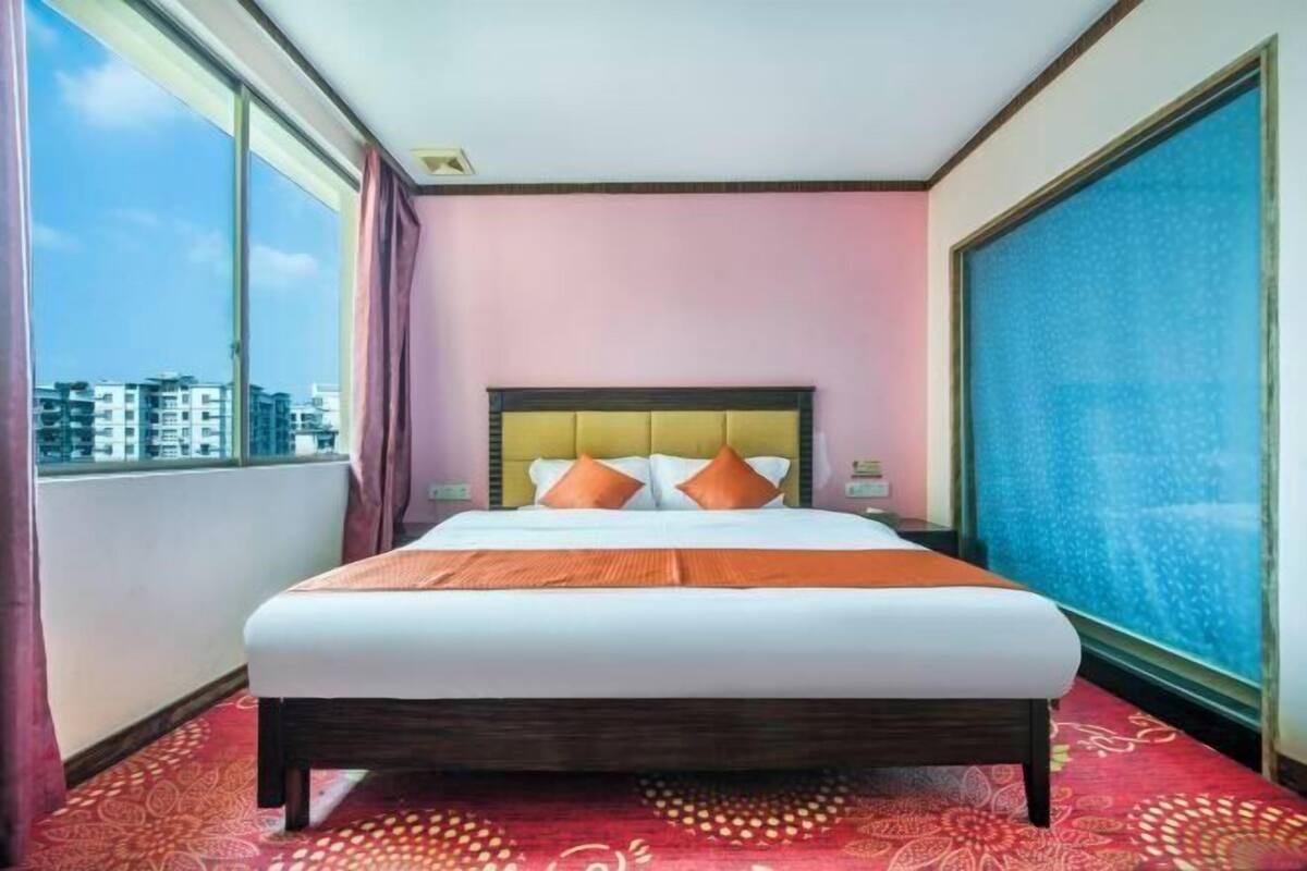 Una camera d'hotel con un letto grande, vista sulla città e un'ampia finestra.