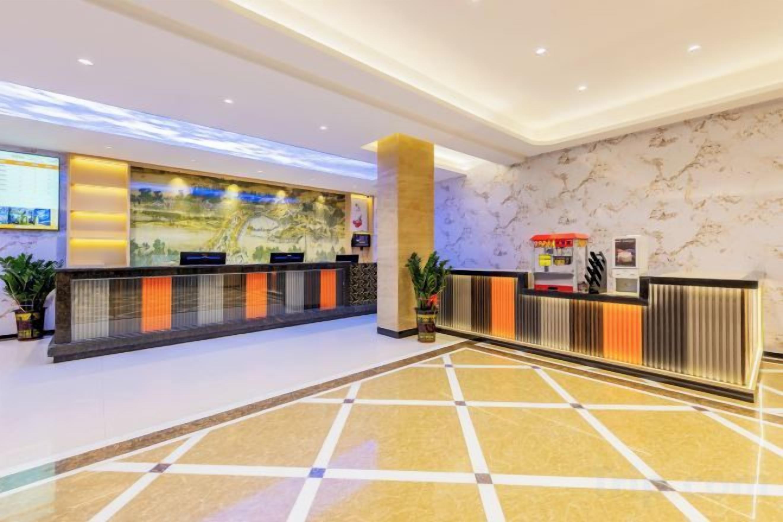 A hotel reception area with a marble wall, a reception desk, and a digital screen.