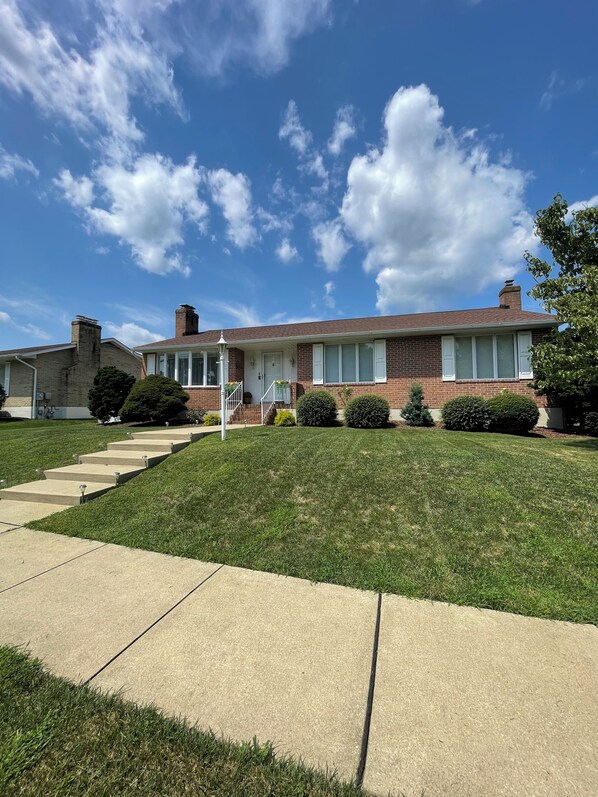 A two-story brick house with a front porch, a well-maintained lawn, and a clear blue sky. - Home in Perry Hall area (Nottingham)