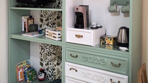 Un mueble color turquesa con un televisor, libros y objetos decorativos.