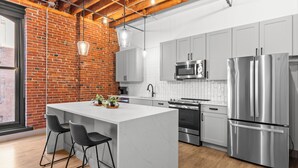 Una cocina moderna con una isla grande, electrodomésticos de acero inoxidable y una pared de ladrillo.