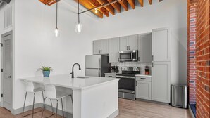 Cocina moderna con armarios blancos, electrodomésticos de acero inoxidable y una isla central con taburetes de bar.