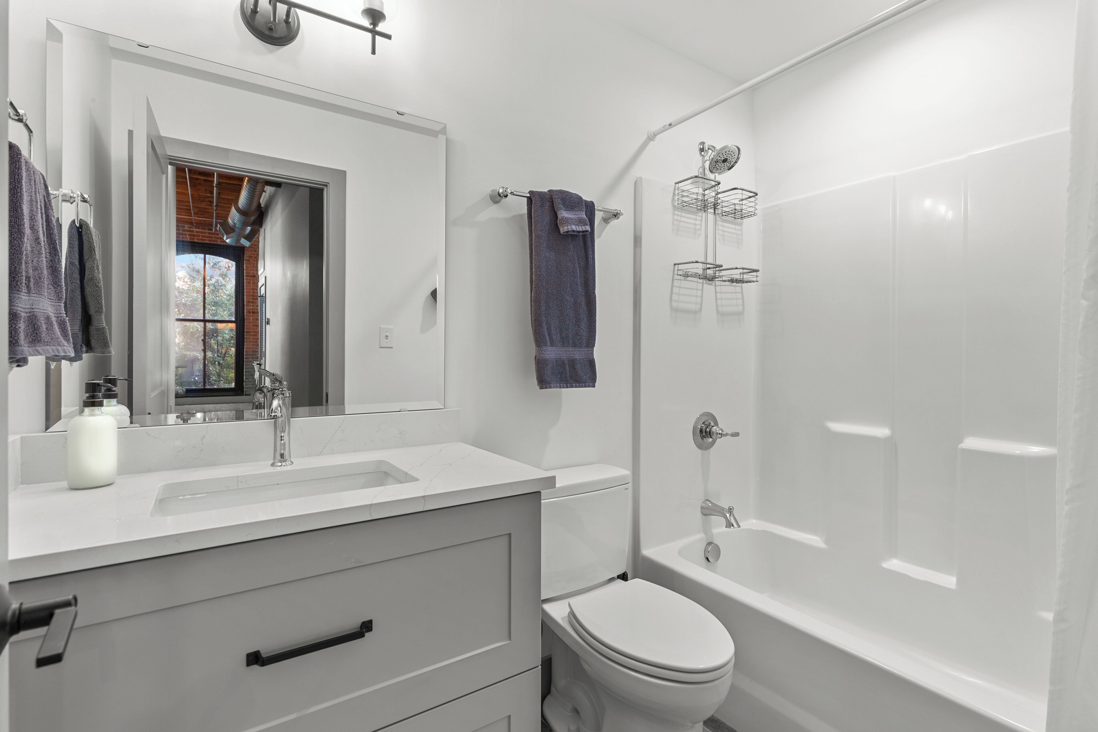 Une salle de bain moderne avec un lavabo blanc, un miroir et des toilettes, une douche avec une paroi en verre et un porte-serviettes avec une serviette bleue.