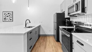 Una cucina moderna con mobili bianchi, un frigorifero nero, un forno a microonde e un fornello.
