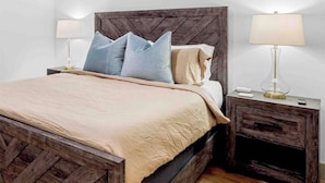 Un letto con testiera in legno, due comodini con lampade e una coperta beige.