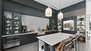 A modern kitchen with dark cabinetry, a central island, and pendant lighting.