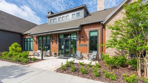 A building with a sign reading "CLUBHOUSE" and outdoor seating with chairs and tables.