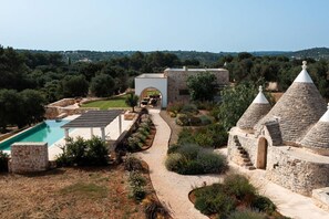 A villa with a swimming pool, stone architecture, and a garden pathway.