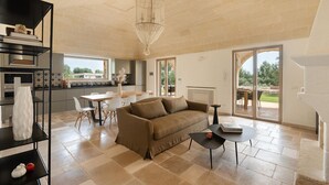 A spacious living area with a sofa, a dining table, and a chandelier. - Villa Cinera - Luxury Villa with private pool (Ostuni)