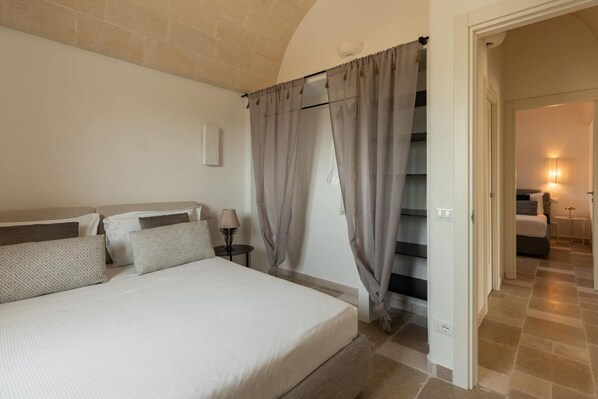 A bedroom with a bed, curtains, a nightstand, and a lamp.
