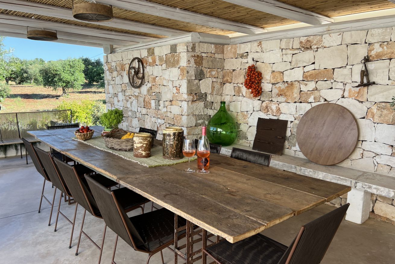Un espace de restauration extérieur de style rustique, avec un mur en pierre, une table en bois et des chaises.