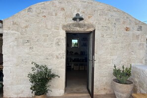 A stone building with a doorway leading to a room with shelves and a window.