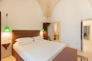 A bedroom with a large bed, green wall-mounted lamps, a wooden headboard, and a wardrobe.