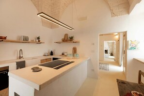 Une cuisine moderne dotée d’un îlot central, d’appareils électroménagers intégrés et d’objets décoratifs disposés sur des étagères.