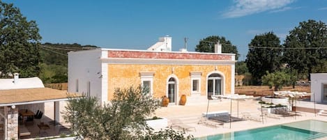 Una villa moderna con piscina, mobiliario exterior y jardín.