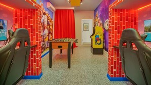 Una habitación con mesa de futbolín, paredes de ladrillo rojo y murales coloridos.
