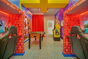 Une pièce avec un baby-foot, des murs en briques rouges et des peintures murales colorées.