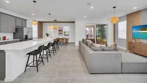 A modern kitchen with a long island, bar stools, and pendant lighting. - Private Theater! Minions Gameroom! MARIO Bunks! Close to Disney! (Kissimmee)