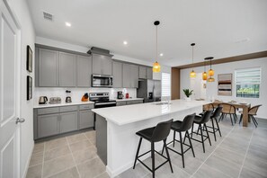 A modern kitchen with grey cabinets, a large island, and bar stools.