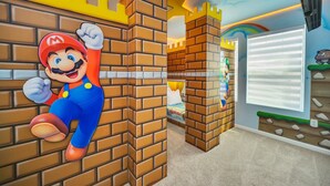 Habitación con pared decorada con ladrillos al estilo Mario y un ventanal grande.
