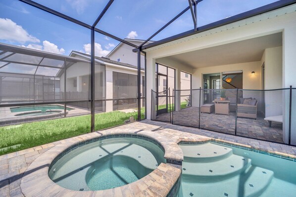 Un espace piscine extérieur moderne, doté de baies vitrées, d’un jacuzzi et d’une terrasse aménagée avec du mobilier d’extérieur.