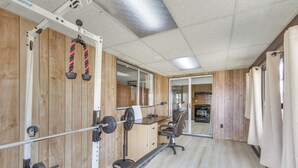 A gym with wooden walls, a weight bench, a squat rack, and a fan. - Pet-Friendly Ridgecrest Home Near OHV Trails! (Ridgecrest)